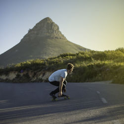 Side view of man skateboarding on road