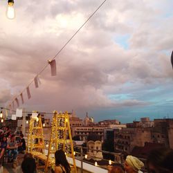 People on illuminated buildings in city against sky