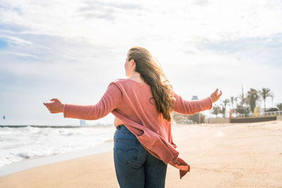 Rear view of woman standing at beach