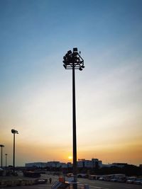 Low angle view of street lights against sky at sunset