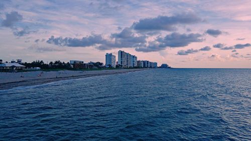 Scenic view of sea and buildings against sky at sunset