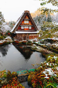 House by lake against sky