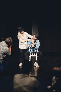 Full length of actress rehearsing with man sitting on chair while rehearsing on stage