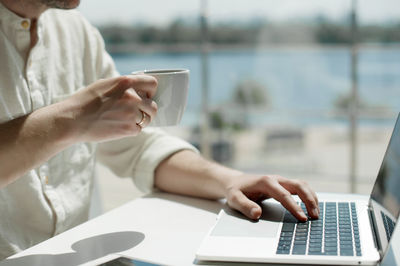 Midsection of man using laptop on table