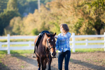 Rear view of woman riding horse on field