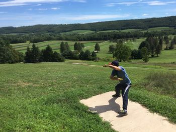 Full length of man playing disc golf on field during sunny day