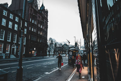 People walking on wet road in city during rainy season