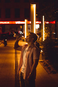 Man standing on street in city at night