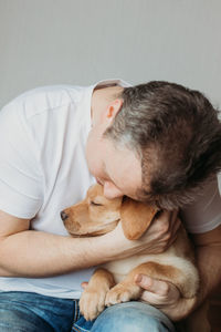 Young man hugging his labrador retriever puppy. the concept of friendship between a dog and a person