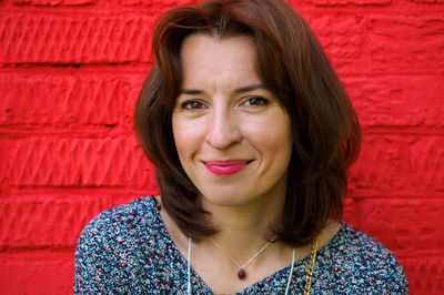 Close-up face of happy smiling woman near red wall