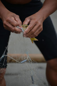 Midsection of man removing fish from fishing net