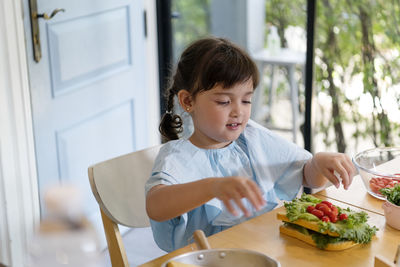 Girl looking away while sitting on table