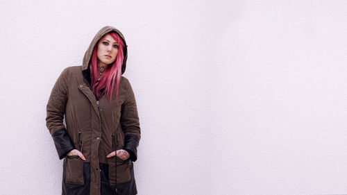 Young woman standing against wall