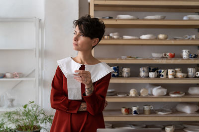 Thoughtful female entrepreneur holding receipt and thinking about pottery shop profitability