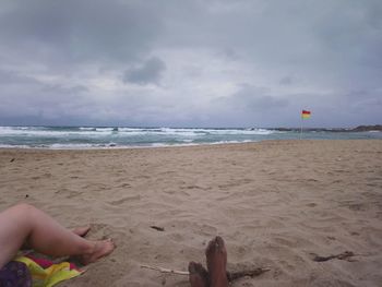 Low section of man on beach against sky