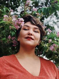 Portrait of woman standing against flowering plant