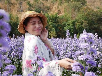 Beautiful woman standing by purple flowering plants