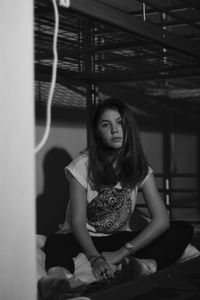 Portrait of young woman sitting on bunk bed