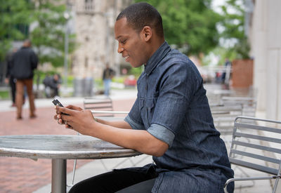 Side view of man using mobile phone in city