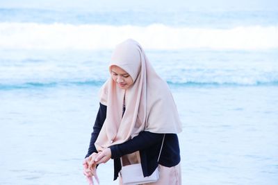 Woman wearing hijab standing against sea