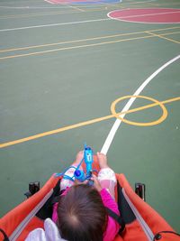 Rear view of baby girl sitting in carriage at basketball court