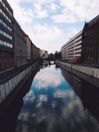 Canal amidst buildings against sky in city