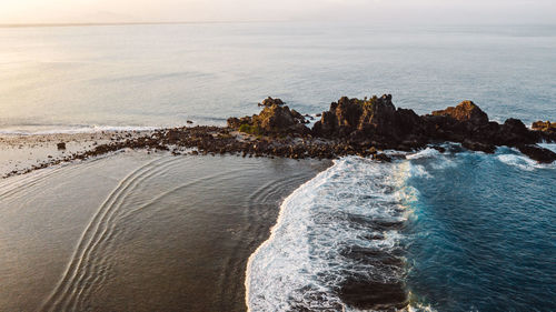 Scenic view of rocks on beach against sky