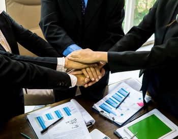 Midsection of business people stacking hands at table