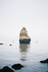 Rock formation in sea against clear sky