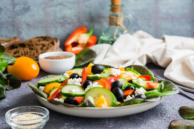 Greek salad of fresh vegetables, leaves and feta cheese on a plate on the table. 