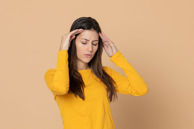 Portrait of beautiful young woman against yellow background