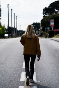 Rear view of woman walking on road in city