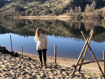 Portrait of woman wearing sunglasses standing by lake