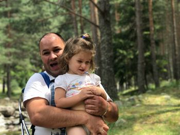 Father and daughter by tree in forest