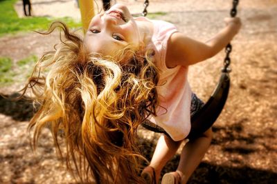 Portrait of cheerful girl playing on swing at playground