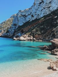 Scenic view of sea and rocks against blue sky