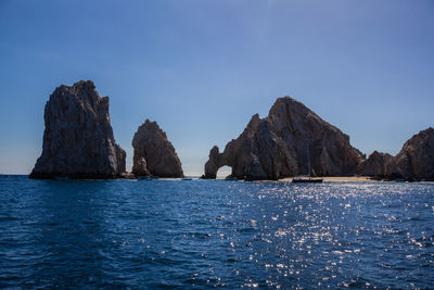 Rock formations in sea against blue sky