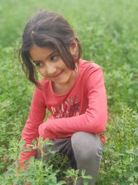 Smiling girl crouching on plants