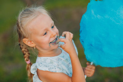 Cute girl holding candy floss while standing outdoors