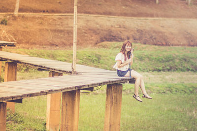 Portrait of woman sitting on footbridge 