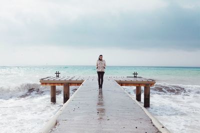 Full length of woman walking on pier over sea against sky