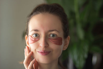 Young woman with pink patches in heart shape under eyes. skin care and valentines day concept.