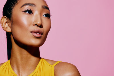 Close-up of young woman against pink background