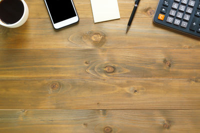 Directly above shot of mobile phone and calculator on wooden table