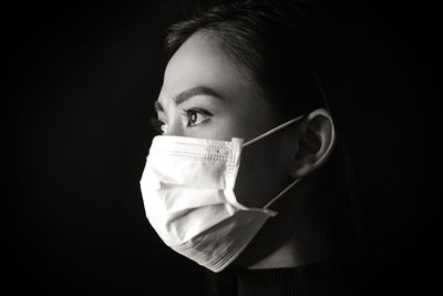 Close-up portrait of young woman against black background