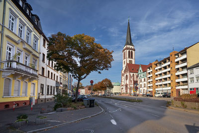 Road by buildings against sky in city