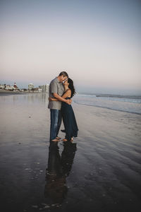 Barefoot loving mid-40's couple on beach embracing face to face negative space