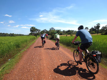 Men riding bicycle on road against sky