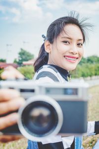 Portrait of a smiling young woman holding camera