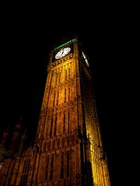 Low angle view of clock tower at night